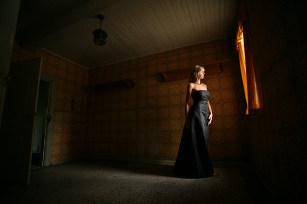 Woman in black dress near window.
