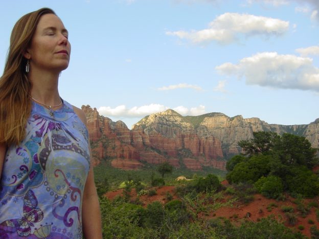 Woman meditating in scenic desert landscape.
