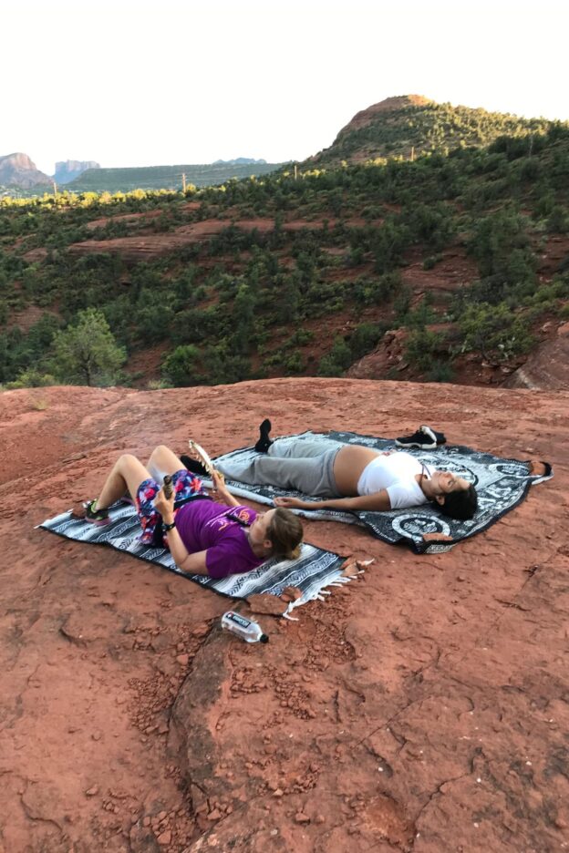 People relaxing on rocky landscape with mats.