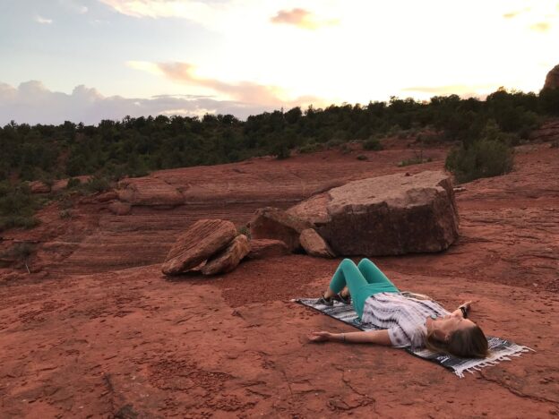 Woman relaxing on red rock landscape.