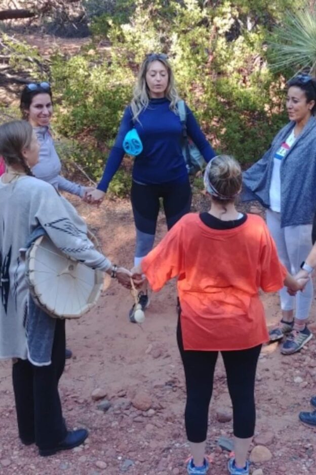 People holding hands in a circle outdoors.