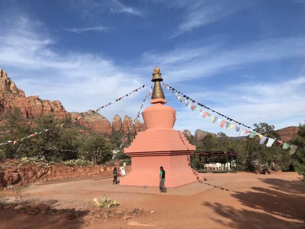 Desert stupa with prayer flags and mountains.